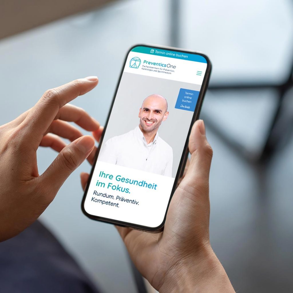 Eine Person hält ein Smartphone mit einer geöffneten PreventicsOne-Website in der Hand.
